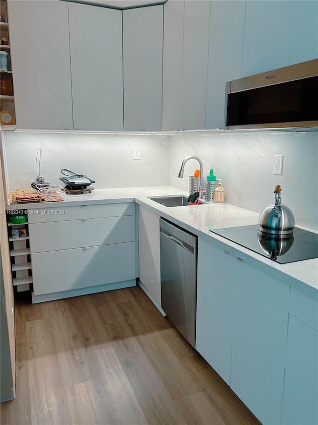 kitchen with sink, light hardwood / wood-style flooring, dishwasher, and decorative backsplash