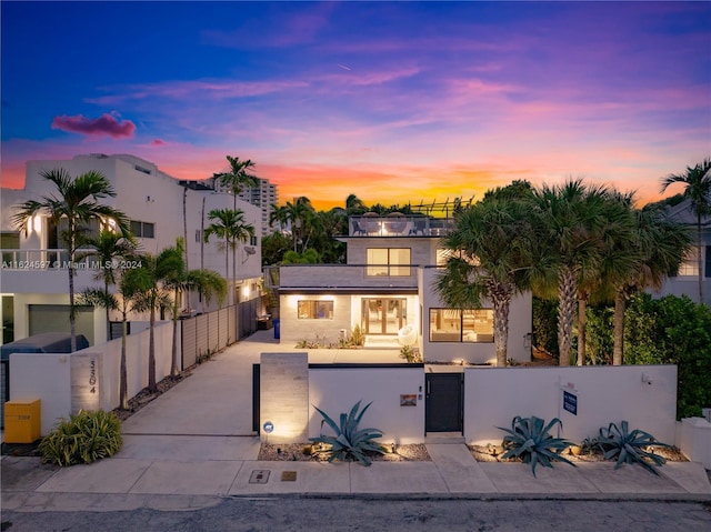 view of front of home featuring a fenced front yard, stucco siding, concrete driveway, a gate, and a balcony