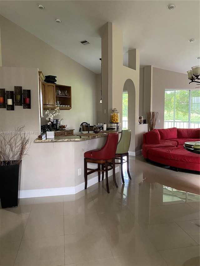 kitchen with vaulted ceiling, kitchen peninsula, light tile patterned flooring, and a breakfast bar