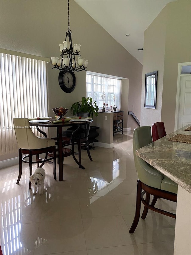 dining area with high vaulted ceiling, an inviting chandelier, and tile patterned flooring