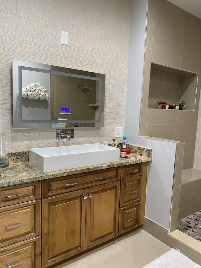 bathroom featuring tile patterned flooring, vanity, and a shower