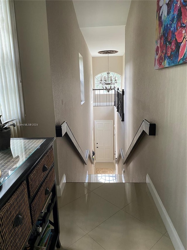 hallway featuring tile patterned flooring and a chandelier