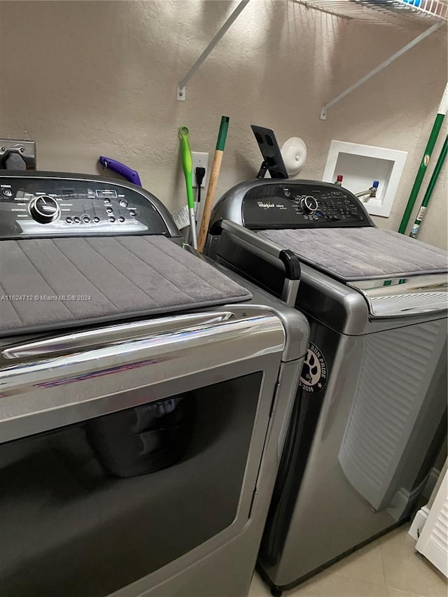 clothes washing area featuring washing machine and clothes dryer and light tile patterned flooring