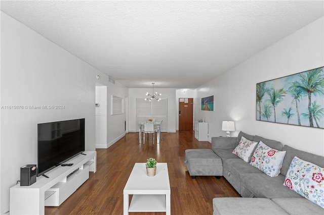 living room featuring a textured ceiling, dark hardwood / wood-style flooring, and a notable chandelier