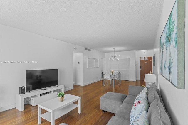 living room featuring hardwood / wood-style flooring, a notable chandelier, and a textured ceiling