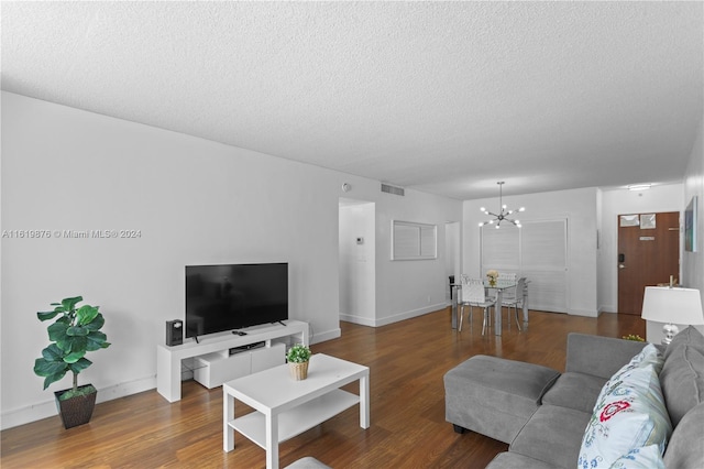 living room with hardwood / wood-style flooring, a notable chandelier, and a textured ceiling