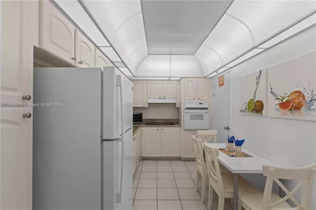 kitchen with light tile patterned flooring, white cabinetry, and white appliances