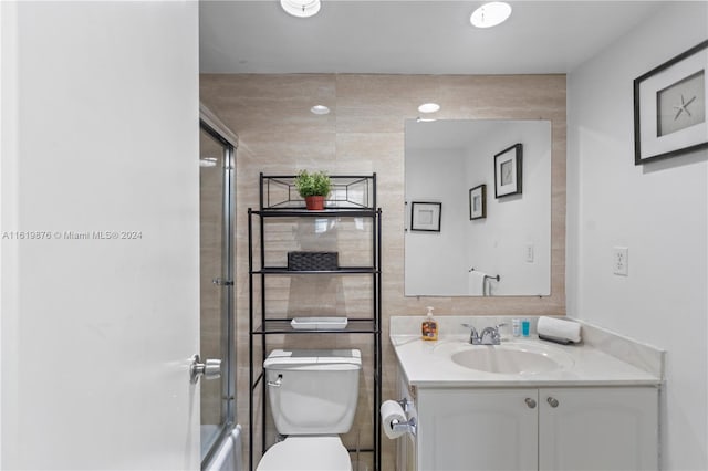 bathroom featuring vanity, tile walls, and toilet