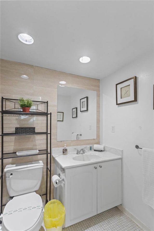 bathroom with tile walls, tile patterned floors, toilet, and vanity