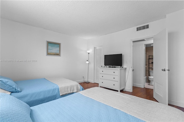 bedroom featuring dark wood-type flooring, connected bathroom, and a textured ceiling