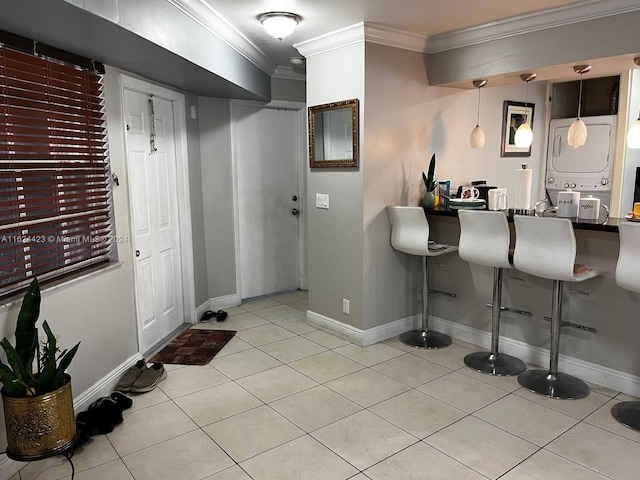 interior space with a breakfast bar area, light tile patterned floors, hanging light fixtures, and ornamental molding