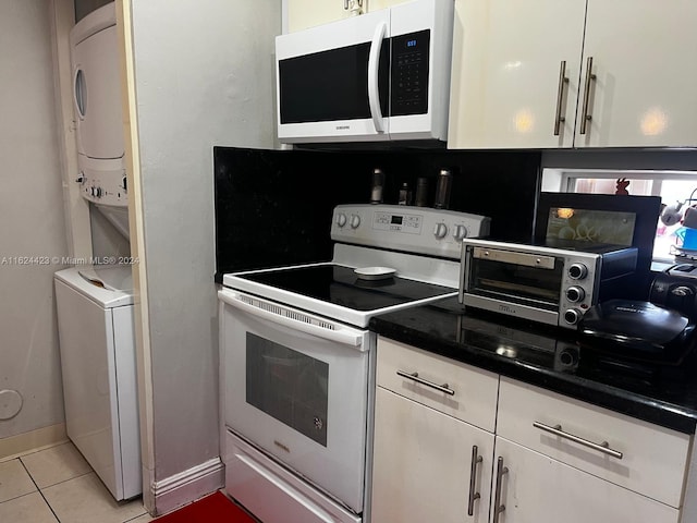 kitchen with white cabinets, light tile patterned floors, white appliances, and stacked washer / drying machine