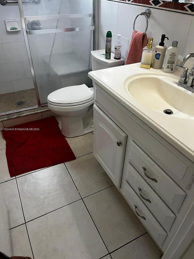 bathroom with tile patterned flooring, vanity, toilet, and a shower with shower door