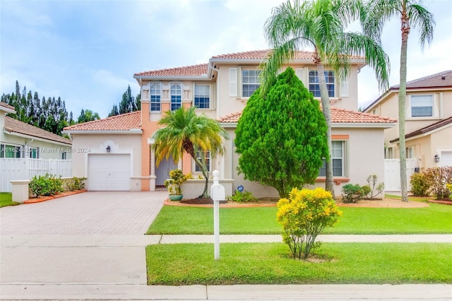 mediterranean / spanish-style house with a tile roof, a front yard, stucco siding, a garage, and driveway