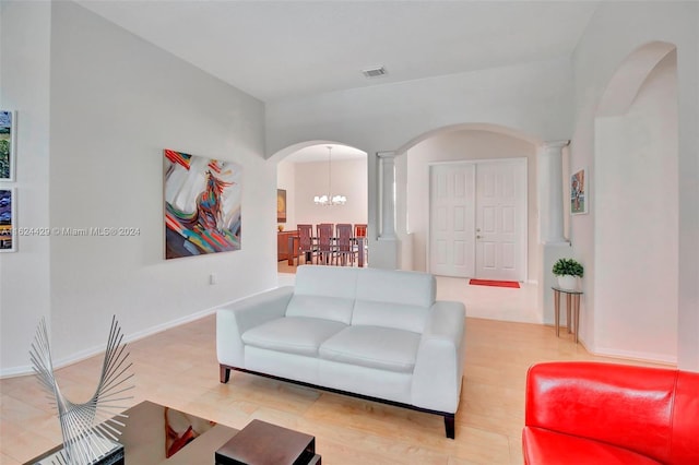 living room featuring baseboards, visible vents, ornate columns, arched walkways, and a chandelier