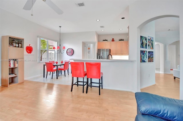 kitchen featuring visible vents, stainless steel fridge with ice dispenser, arched walkways, ceiling fan, and light brown cabinetry