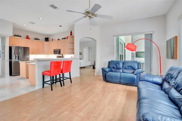 living area with light wood finished floors, visible vents, recessed lighting, arched walkways, and a ceiling fan