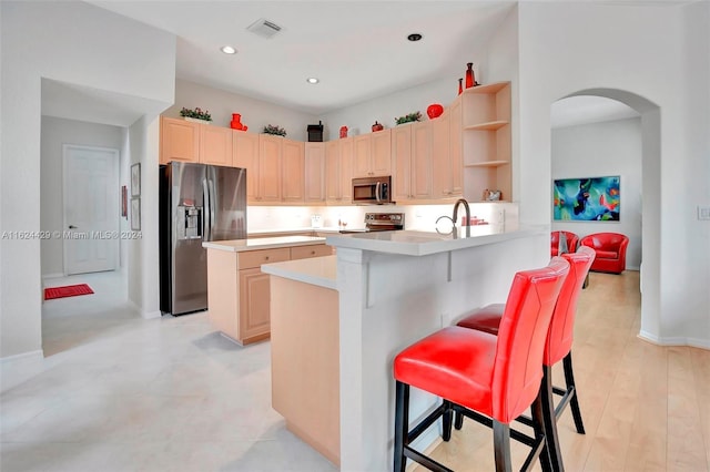 kitchen featuring visible vents, open shelves, stainless steel appliances, arched walkways, and light countertops