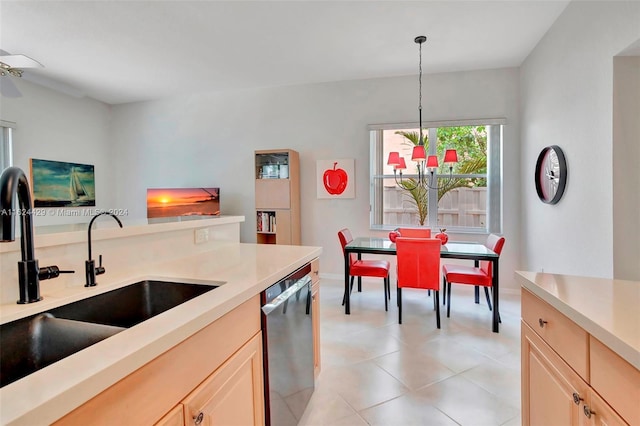 kitchen featuring a sink, decorative light fixtures, stainless steel dishwasher, and light countertops