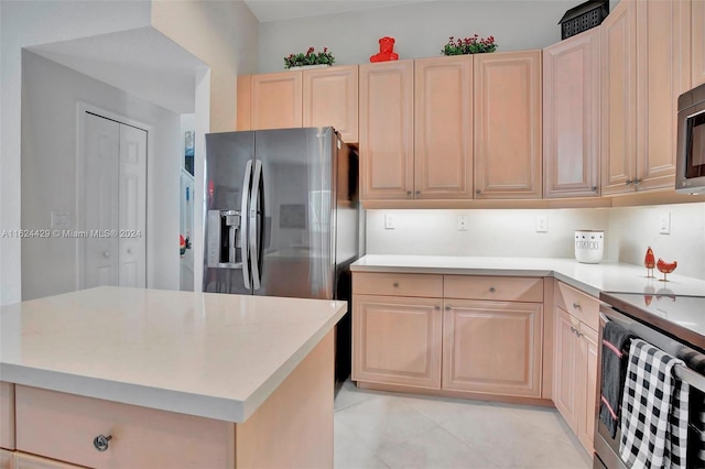 kitchen featuring light brown cabinets, a center island, appliances with stainless steel finishes, light tile patterned flooring, and light countertops