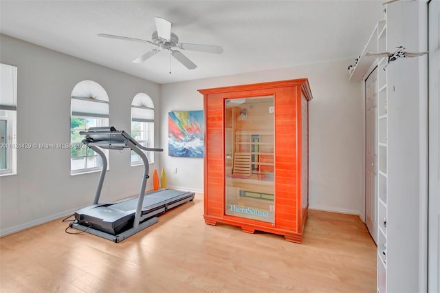 workout room with baseboards, light wood-type flooring, and ceiling fan