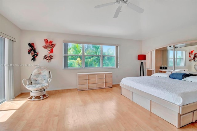 bedroom featuring baseboards, arched walkways, wood finished floors, and a ceiling fan