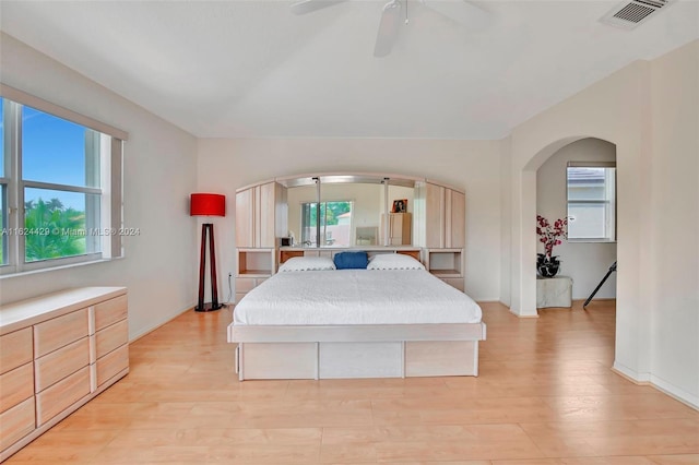 bedroom with visible vents, arched walkways, a ceiling fan, and light wood finished floors