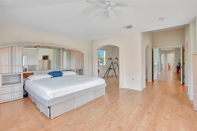 bedroom with baseboards, visible vents, arched walkways, ceiling fan, and light wood-type flooring