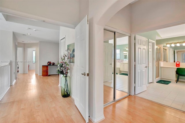 hall featuring light wood-type flooring and arched walkways