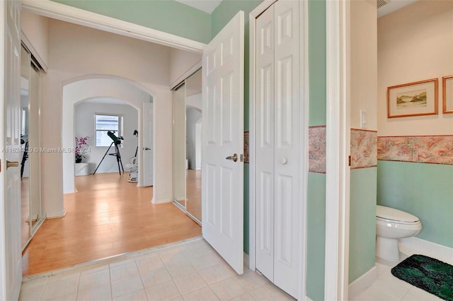 hall featuring arched walkways and light tile patterned floors