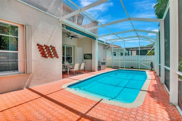 view of pool with glass enclosure, a patio area, a fenced in pool, and a ceiling fan