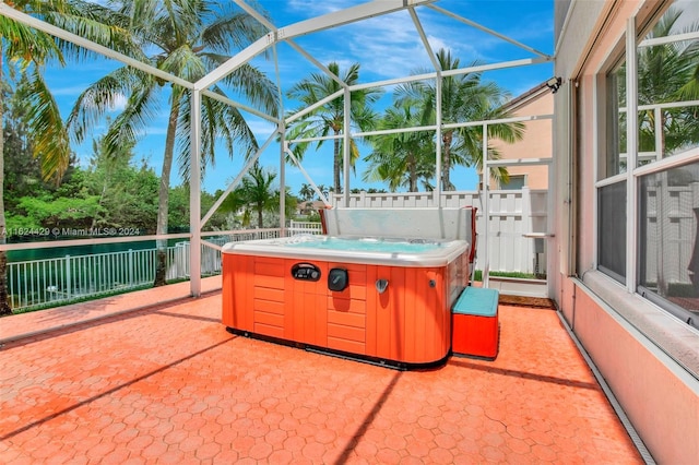 view of patio featuring glass enclosure and a hot tub