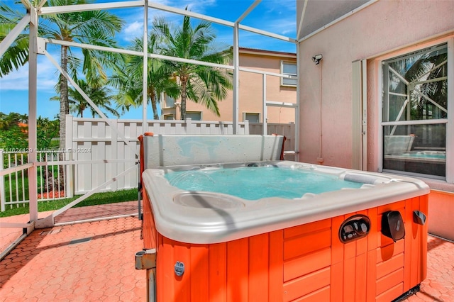 view of patio / terrace with a lanai, a hot tub, and fence