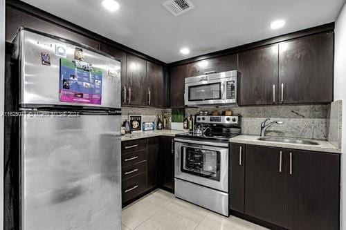 kitchen featuring dark brown cabinets, sink, appliances with stainless steel finishes, and tasteful backsplash