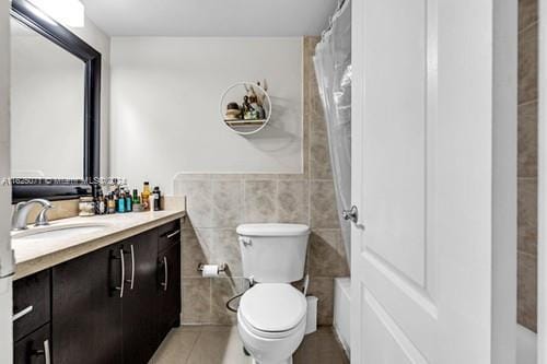 bathroom with tile patterned floors, vanity, tile walls, and toilet