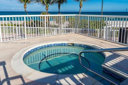 view of pool with a water view and an in ground hot tub