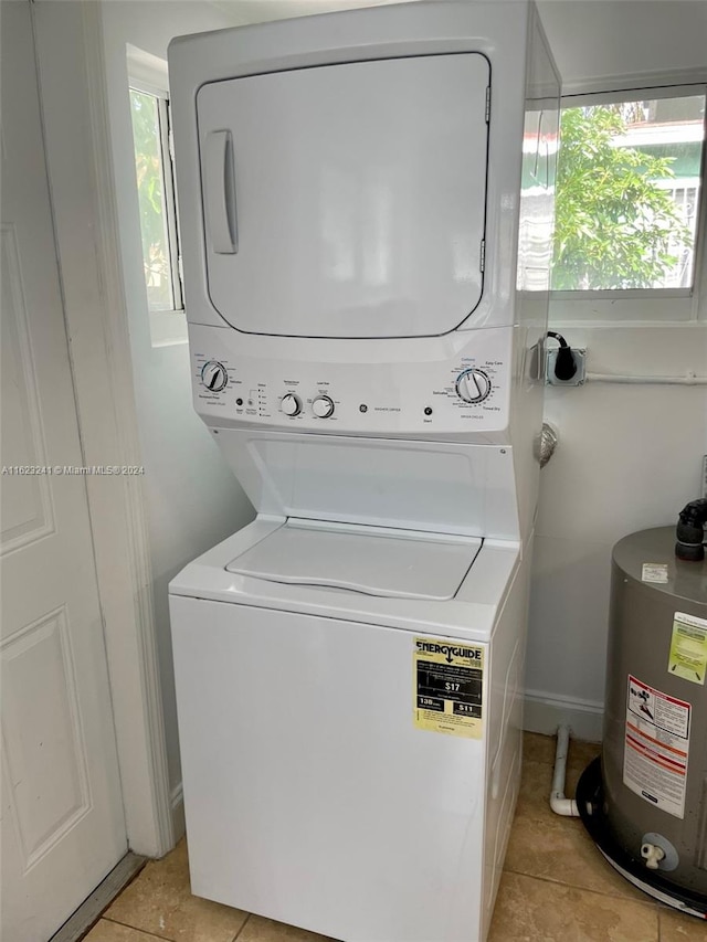 laundry room with stacked washer and dryer, light tile patterned flooring, and water heater