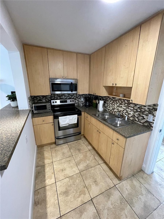 135 NW 68th St, Miami, FL 33150 - kitchen with appliances with stainless steel finishes, light brown cabinets, dark countertops, and decorative backsplash