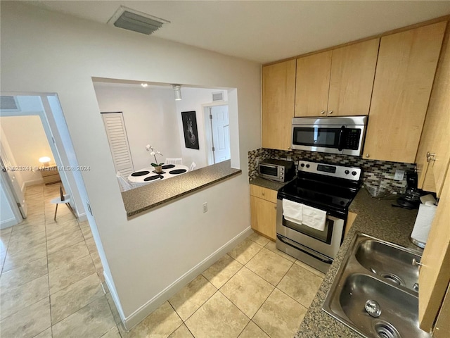 kitchen featuring stainless steel appliances, sink, backsplash, light tile patterned floors, and light brown cabinetry