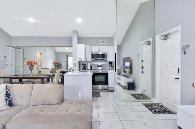 kitchen featuring lofted ceiling, white cabinets, appliances with stainless steel finishes, and light tile patterned floors