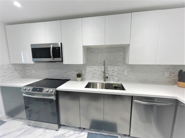 kitchen with sink, white cabinets, backsplash, and stainless steel appliances