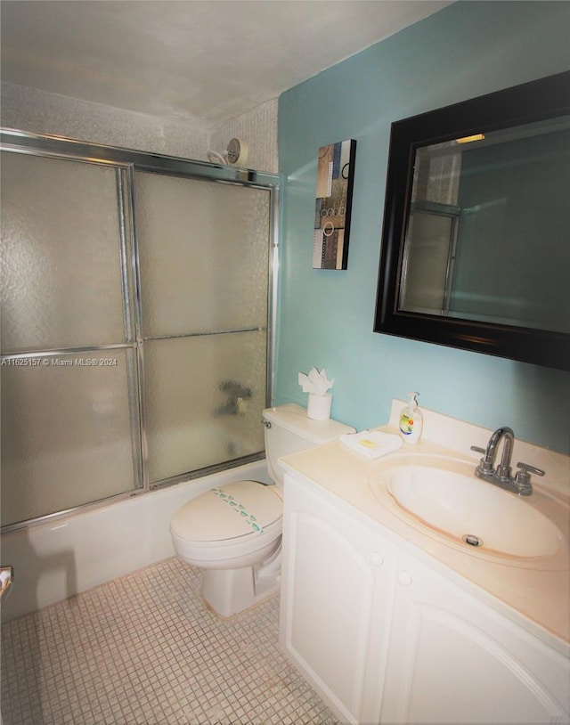 full bathroom featuring tile patterned floors, vanity, enclosed tub / shower combo, and toilet