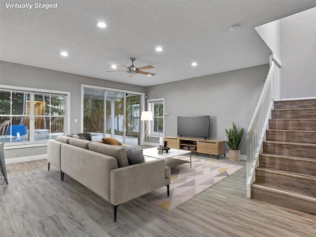 living room featuring ceiling fan, a textured ceiling, and light hardwood / wood-style floors