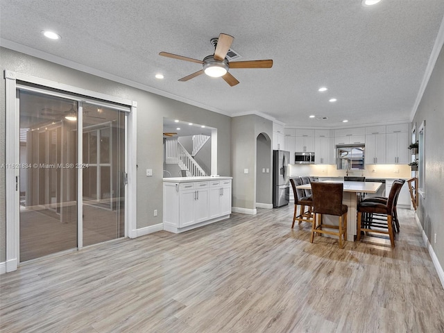 dining room featuring ornamental molding, ceiling fan, a textured ceiling, and light hardwood / wood-style floors