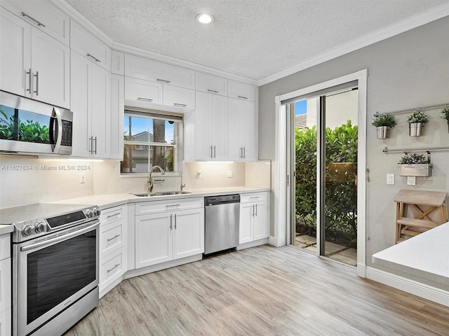 kitchen with stainless steel appliances, plenty of natural light, white cabinets, and sink