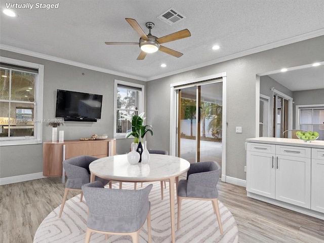 dining space with ornamental molding, light wood-type flooring, a textured ceiling, and ceiling fan