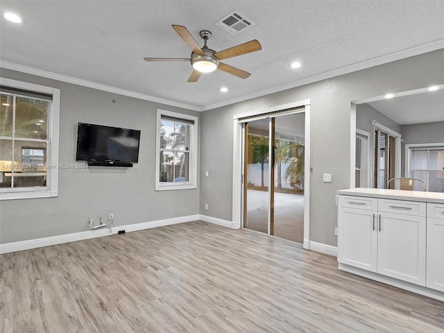 unfurnished living room featuring light hardwood / wood-style floors, ceiling fan, a textured ceiling, and crown molding