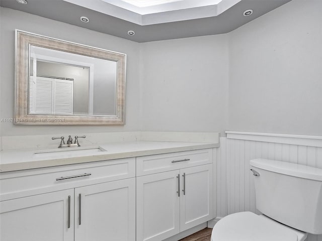 bathroom with toilet, vanity, and hardwood / wood-style flooring