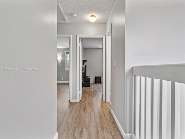 corridor with light hardwood / wood-style floors and a textured ceiling