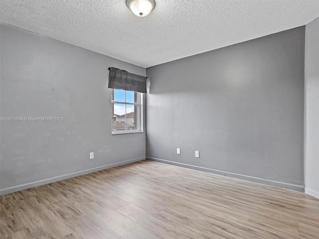 spare room featuring a textured ceiling and light hardwood / wood-style floors